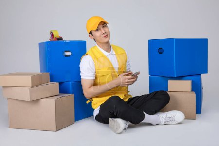 millennials and gen z, korean asian young man resting next to moving boxes