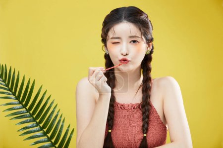 beauty concept photo of korean asain beautiful woman winking while holding a lipgloss, studio background