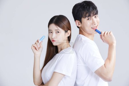 korean asian young couple holding lipbalm, studio background