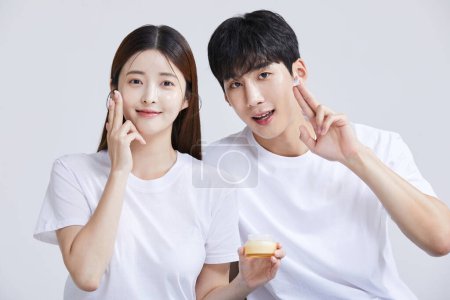 korean asian young couple with creems, cosmetics, studio background