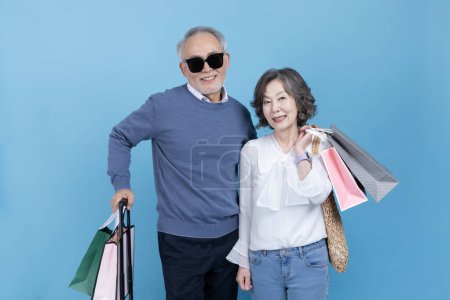 Senior portant une valise et un sac à provisions