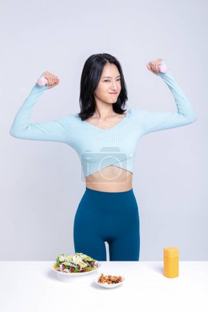 A woman holding an dumbbell in front of a salad nut pillbox