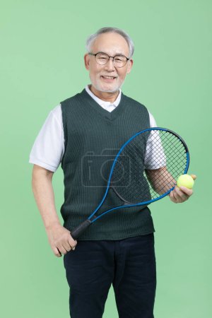 A senior male holding a tennis racket and a tennis ball