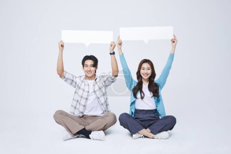 A man and a woman sitting with a cross legged empty message paper