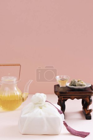 There is a plate of rice cake on the tea table, a wooden fork, a kettle, and a gift cloth