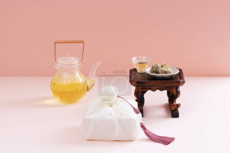There is a plate of rice cake on the tea table, a wooden fork, a kettle, and a gift cloth