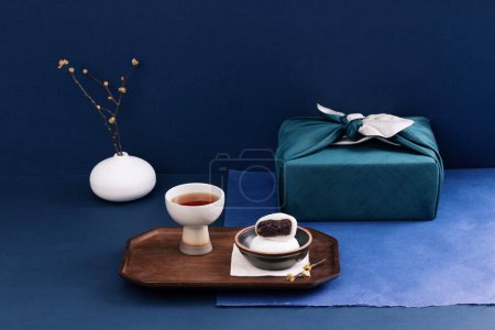 There is rice cake and tea in front of the gift cloth