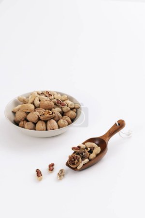 Walnuts and peanuts are served in plates and wood spoon