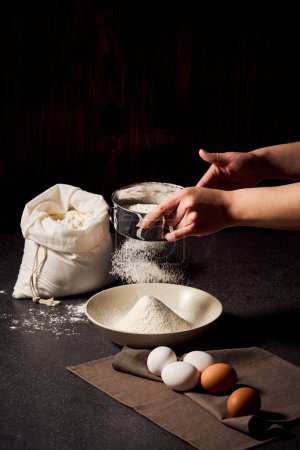 Le processus de tamisage de la farine avec les deux mains vue rapprochée