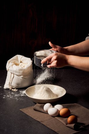 Le processus de tamisage de la farine avec les deux mains vue rapprochée