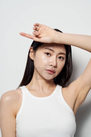 an Asian woman with one hand on her forehead against a white background