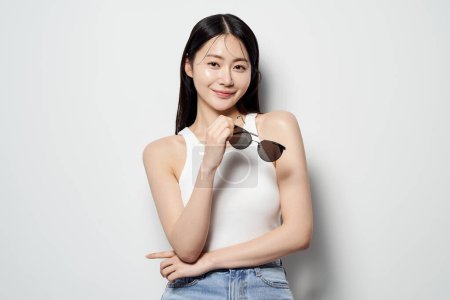 an Asian woman holding sunglasses and smiling