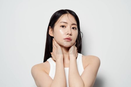an Asian woman with her hands around her neck and staring straight ahead