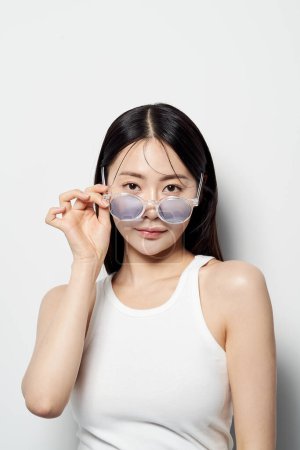 Asiatique femme fixer droit devant avec des lunettes de soleil dans une main
