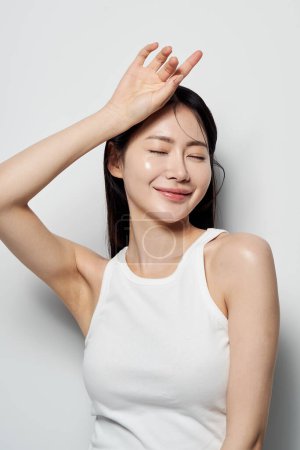 asiatique femme poses avec son yeux fermé et son mains sur son tête