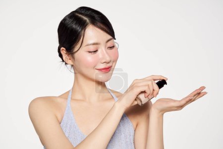 una mujer asiática que aplica fundación a sus palmas
