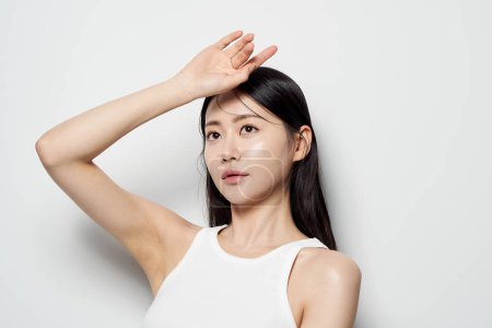 eine Asiatin posiert mit den Händen auf dem Kopf