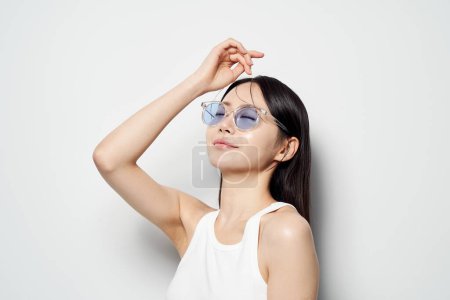 une femme asiatique portant des lunettes de soleil et fermant doucement les yeux