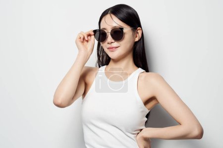 eine Asiatin, die eine Sonnenbrille mit einer Hand trägt