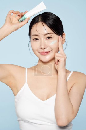 asiatique femme poses avec crème autour son yeux