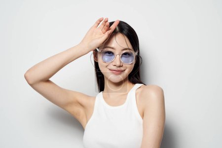 une femme asiatique portant des lunettes de soleil et souriant