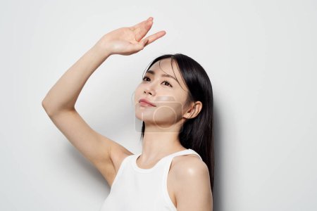Femme asiatique posant avec ses mains en l'air sur un fond blanc