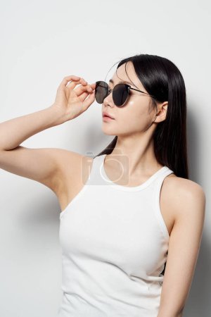 an Asian woman in a white sleeveless shirt and sunglasses