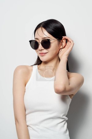 an Asian woman who wears sunglasses against a white background and flips her hair