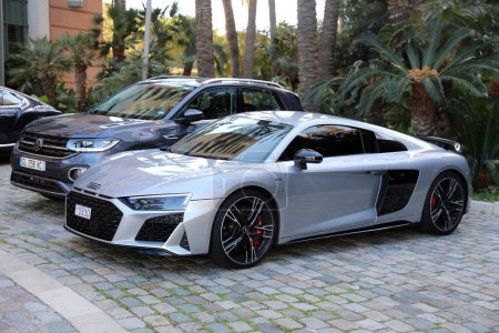Photo for Monte-Carlo, Monaco - April 16, 2023: A sleek gray Audi R8 Coupe V10 performance quattro parked beside a Volkswagen Touareg SUV, showcasing contrasting automotive styles, Monaco - Royalty Free Image