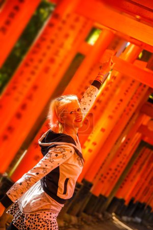 Photo for Buddhist temple defocused background. Adventure, exploration, travel concept. Happy tourist woman under red torii gates with blurred motion effect. Fushimi Inari shrine, Kyoto, Japan. - Royalty Free Image