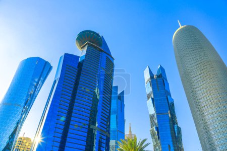 Photo for Doha, Qatar - February 20, 2019: bottom view of Al Fardan Towers complex and Doha Tower, iconic glassed high rises in West Bay. Skyscrapers of Financial District in Middle East at sunset light. - Royalty Free Image