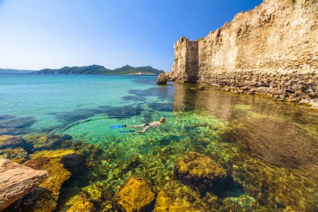 Bikini femme plongeant dans les rochers autour du château de Methoni, une fortification médiévale dans le port de Methoni, Messénie, Péloponnèse, Grèce. Snorkeler femelle nage dans l'eau cristalline. Activité de sports nautiques d'été
