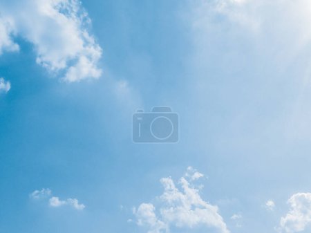 Photo for Summer sky with fluffy clouds as background. The sun radiates its brilliance, enveloping the scene in a warm glow. Drifting clouds add a sense of movement to the serene setting. - Royalty Free Image