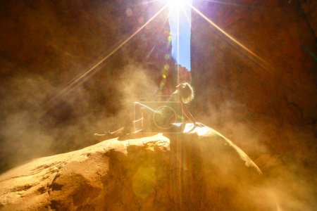 Foto de Mujer turista sentada en una roca con efectos de luz solar con arena volando en el desfiladero natural de Standley Chasm, West MacDonnell Ranges. Australian outback Red Center, Territorio del Norte, Australia. - Imagen libre de derechos