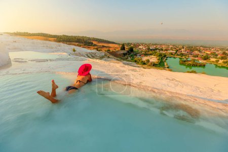 Foto de Mujer turística encuentra un momento de tranquilidad mientras se sumerge en aguas cristalinas de piscinas naturales de pavos en Pamukkale. Rodeado de impresionantes terrazas blancas, creando un ambiente surrealista. - Imagen libre de derechos