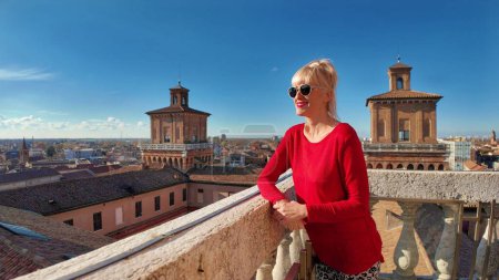 Photo for Tourist woman visiting Ferrara Castle climbed spiral staircase of Lions Tower and reached top of Estense fortress, gazing at the stunning view of the city, with its red roofs and ancient churches. - Royalty Free Image