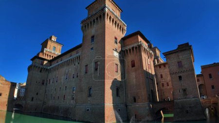 Constructed in 1385, the Castello Estense, Ferrara Castle, stands as medieval stronghold in the heart of Ferrara, Italy. Surrounded by water, features large main structure accompanied by four towers