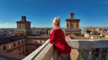 Photo for Tourist woman visiting the Ferrara castle of Italy. Surrounded by wide moat filled with water, which gives it a sense of isolation and protection. The castle has a square shape with 4 massive towers. - Royalty Free Image