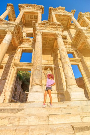 A tourist girl marvels at the Library of Celsus in Ephesus of Turkey. She explores the ruins, immersing herself in the rich history of Ephesus: Unesco world heritage site.