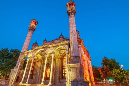 Bañada por el suave resplandor de la luz de la luna, la Mezquita Aziziye Camii de Konya en Turquía. Su exterior está adornado con intrincadas tallas de piedra y patrones geométricos, creando un espectáculo fascinante.