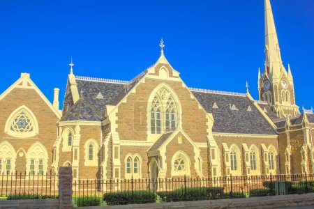 Foto de Fachada lateral de la iglesia madre reformada gótica victoriana en Graaff-Reinet, Cabo Oriental, Gran Karoo, Sudáfrica. Iglesia histórica holandesa, construida en 1886, en el centro de la ciudad. Día soleado con cielo azul - Imagen libre de derechos