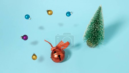 Foto de Árbol de Navidad, adornos flotantes y campana roja sobre fondo pastel cian. Composición horizontal mínima, Navidad y Año Nuevo concepto de celebración abstracta - Imagen libre de derechos
