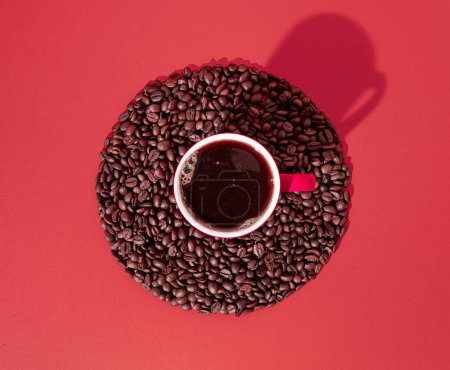 Foto de Cup of black coffee and coffee beans in circle on red background. Minimal horizontal flat lay composition, coffee culture concept - Imagen libre de derechos