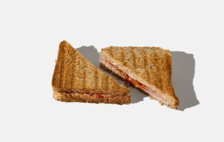Foto de Sandwich tostado cortado por la mitad sobre fondo blanco. Composición horizontal mínima, concepto casero de comida rápida - Imagen libre de derechos
