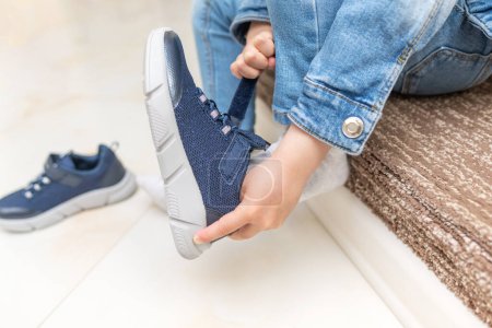 Kinder ziehen Turnschuhe an, wenn sie Schuhe anziehen. Nahaufnahme.