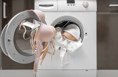 Foto de Lavando un sujetador en una lavadora. Hay una cubierta para ropa de cama. - Imagen libre de derechos