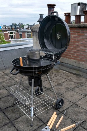 Hervidor de carbón compacto negro con verduras fritas Alójese en la terraza, en el jardín o en la azotea.