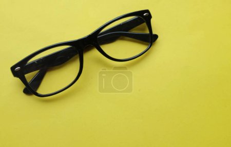 Téléchargez les photos : Gros plan et plat déposer un moderne lunettes, lunettes, lunettes, lunettes montures noires mode pour les hommes et les femmes sur le fond jaune vif - en image libre de droit