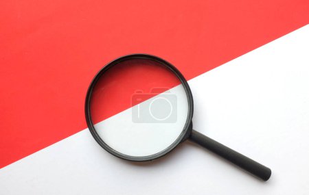 schwarzer Rahmen eine Lupe auf rechteckigem Papier mit weißem und rotem Hintergrund
