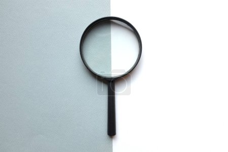 black frame a magnifying glass on rectangle shape colored paper white and gray pastel background